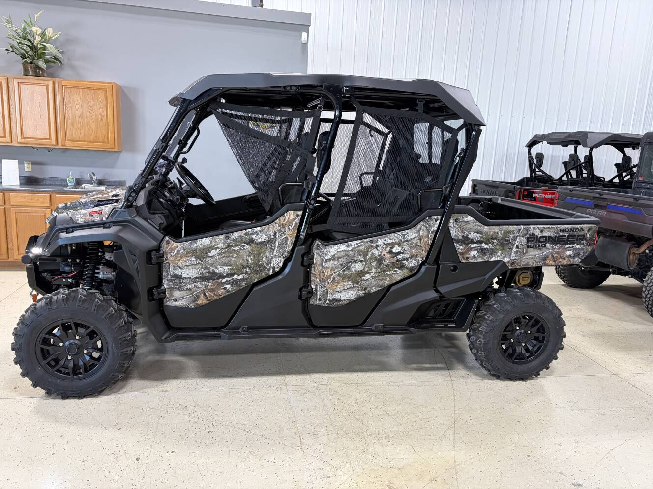A photo of this 2025 Honda® Pioneer 1000-6 Deluxe Crew Truetimber Atera Camo